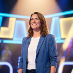 Une femme souriante portant un blazer bleu sur le plateau de l'émission Les 12 Coups de midi.